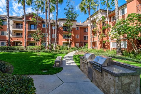 A sunny day at a residential complex with a pathway and grassy area.